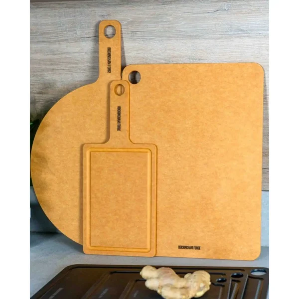 Orange cutting boards with integrated handles and hanging holes resting on a wooden surface.