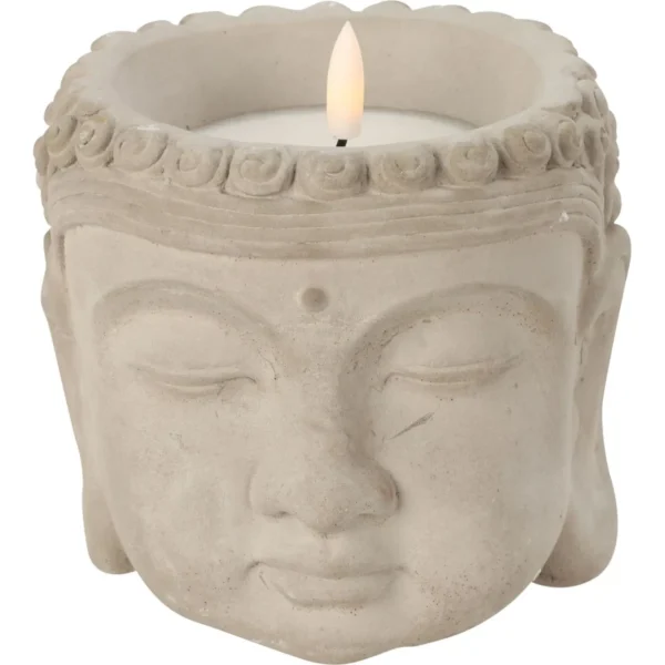Buddha head candle holder with a lit candle on top.