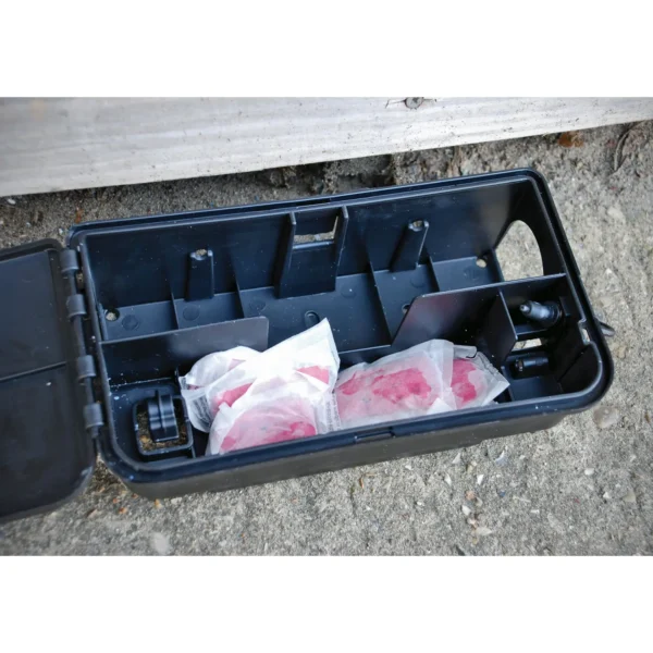 Open black plastic tool/storage box on dirt ground, with crumpled white bags stained pink inside.
